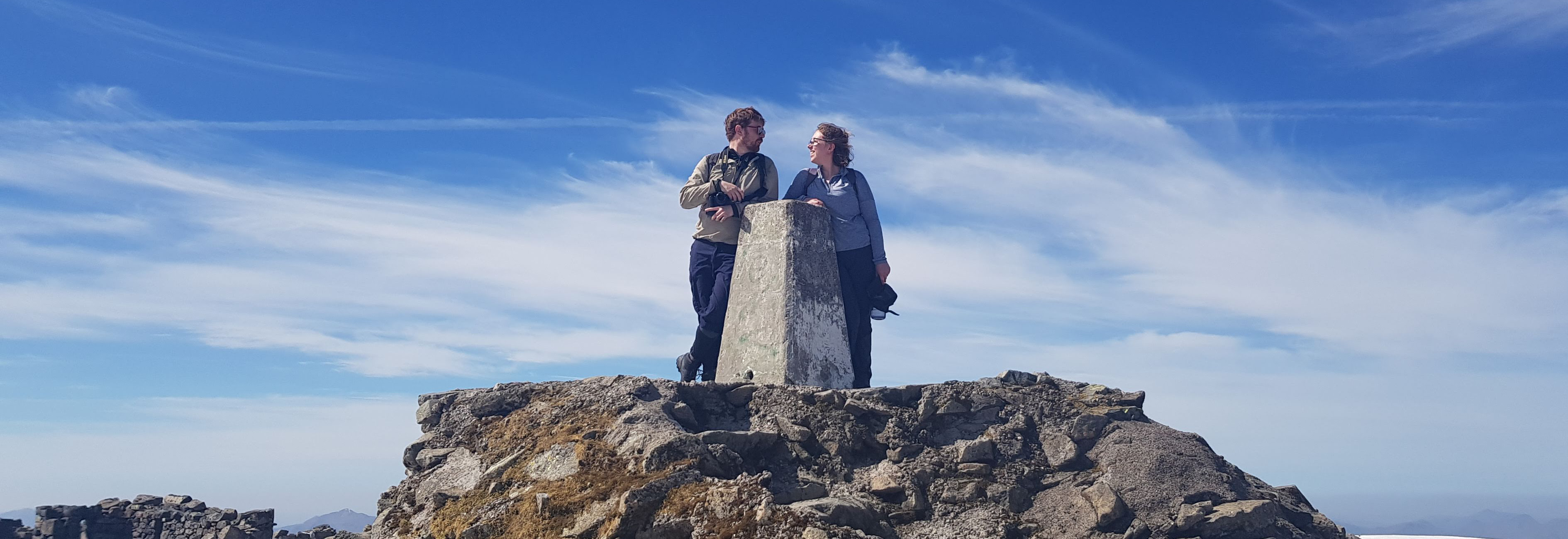 Jo & Neil standing on top of Ben Nevis looking into each other's eyes